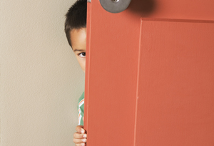 Boy hiding behind door